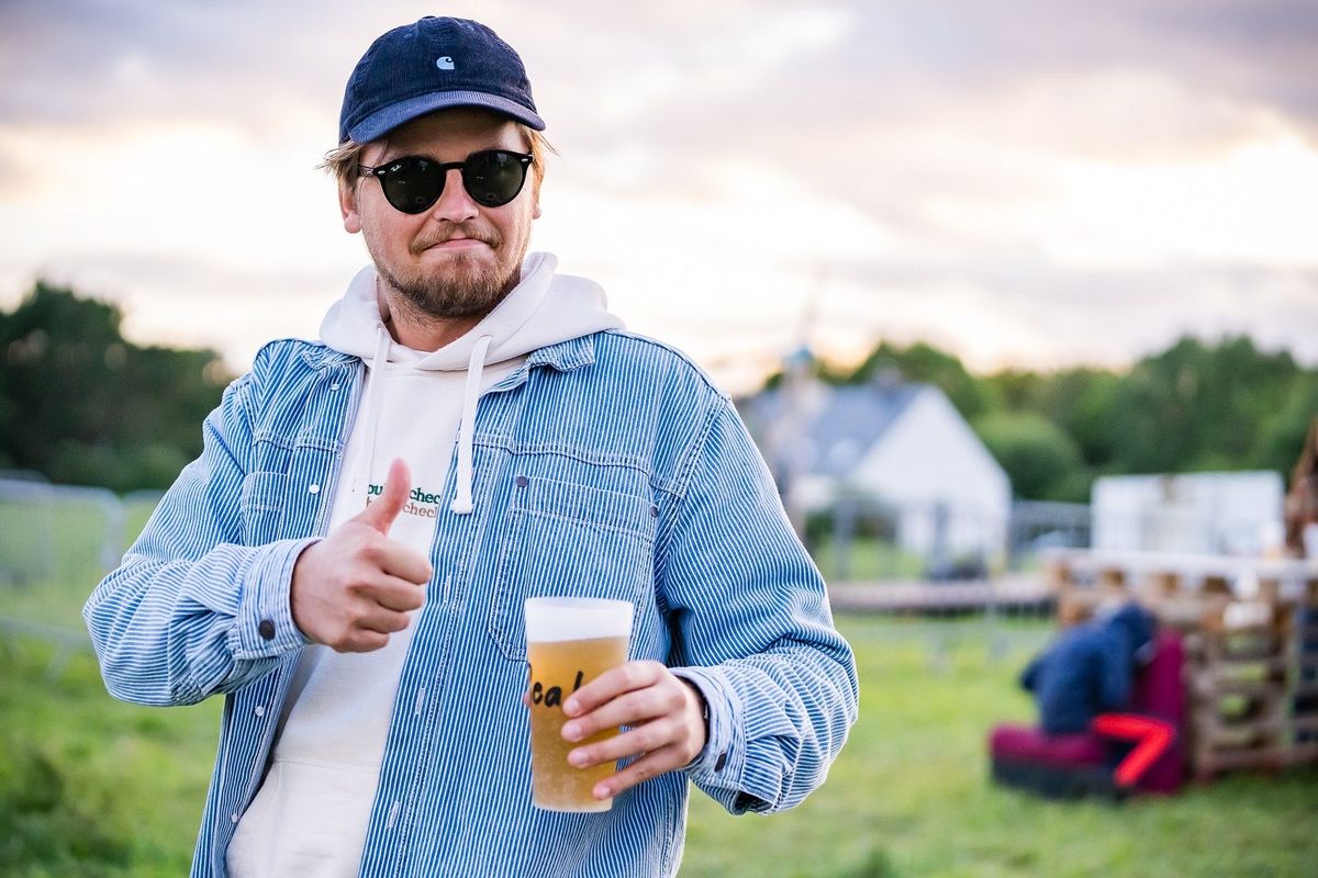 Festivalier souriant avec une bière au coucher de soleil